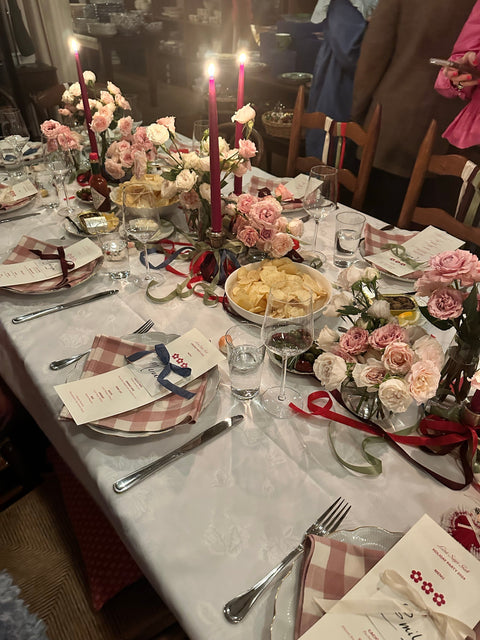 dinner party at a table set with plates, menus, flowers, candles, and wine glasses